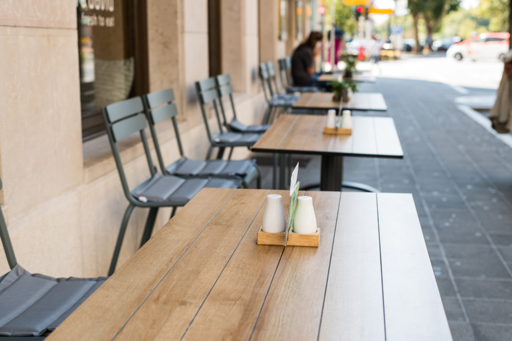 Typical summer outdoor cafe. Tables and chairs summer cafe, restaurant on streets of city in anticipation of visitors. Interior cafe with outdoor area.